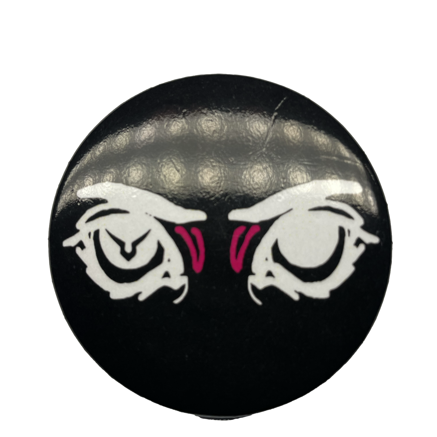 A round pin with a black background featuring an eye design with pink irises and a logo resembling a stylized face in the center.