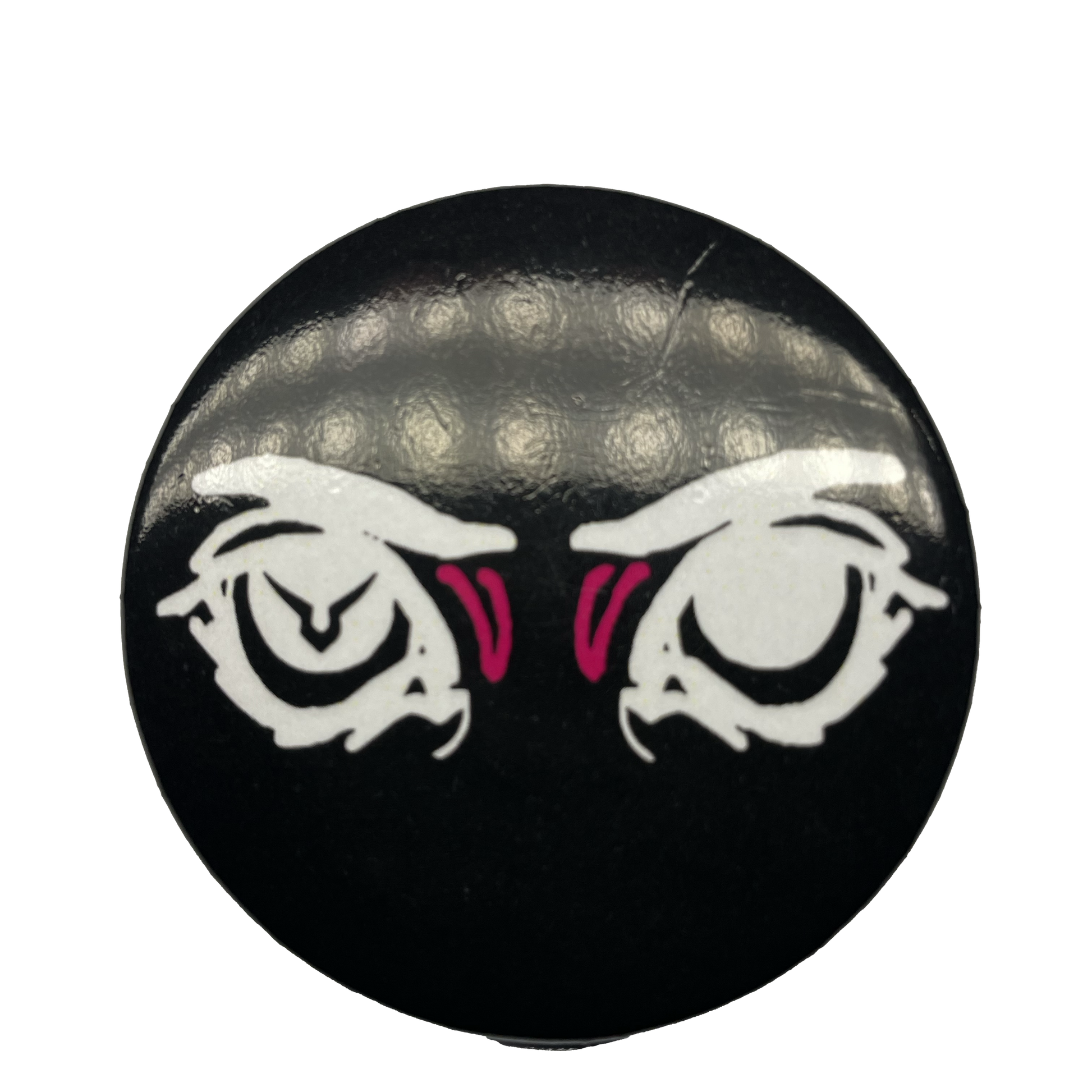 A round pin with a black background featuring an eye design with pink irises and a logo resembling a stylized face in the center.