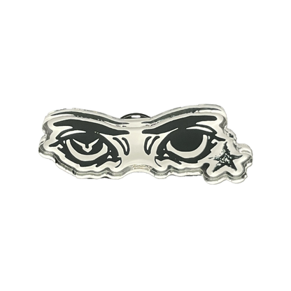 A silver-colored acrylic pin with a soft PVC clutch, featuring a stylized eye design behind a mask-like border.